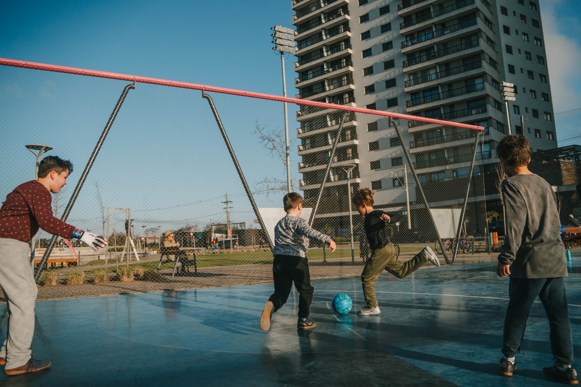 Crianças jogando futebol na quadra poliesportiva do Parque Una