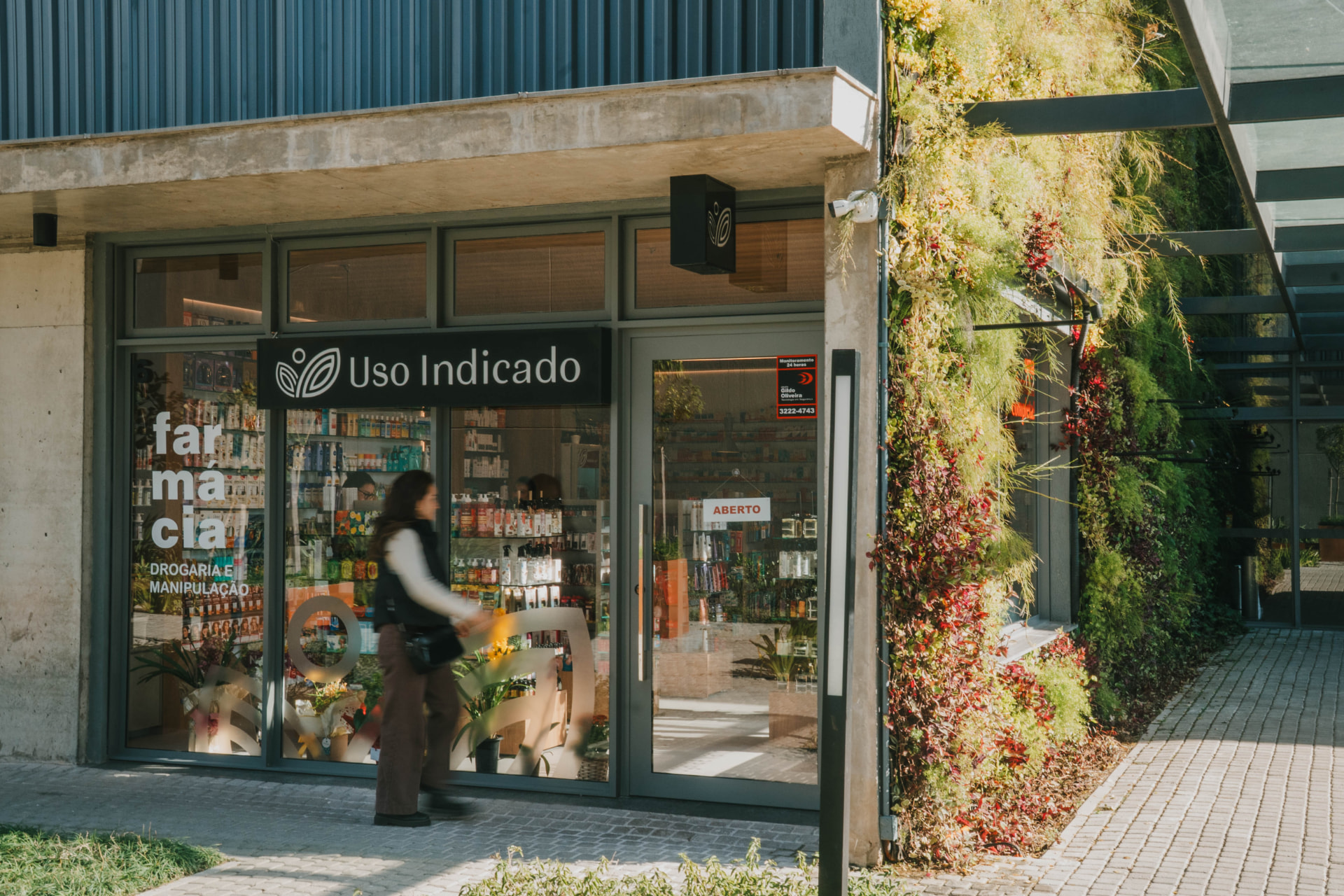 Fachada da farmácia Uso Indicado, no Parque Una, junto a um jardim vertical