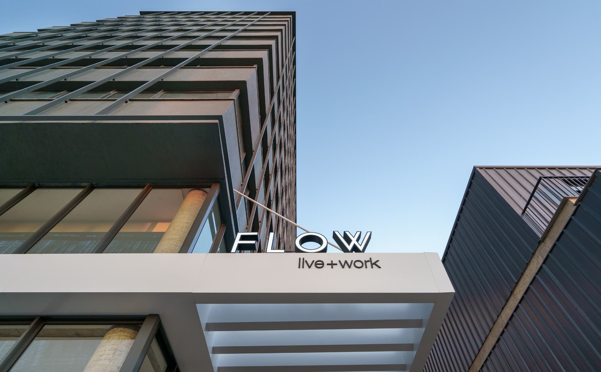 Fachada do Flow Live + WORK, no Parque Una, vista de baixo com o letreiro do prédio