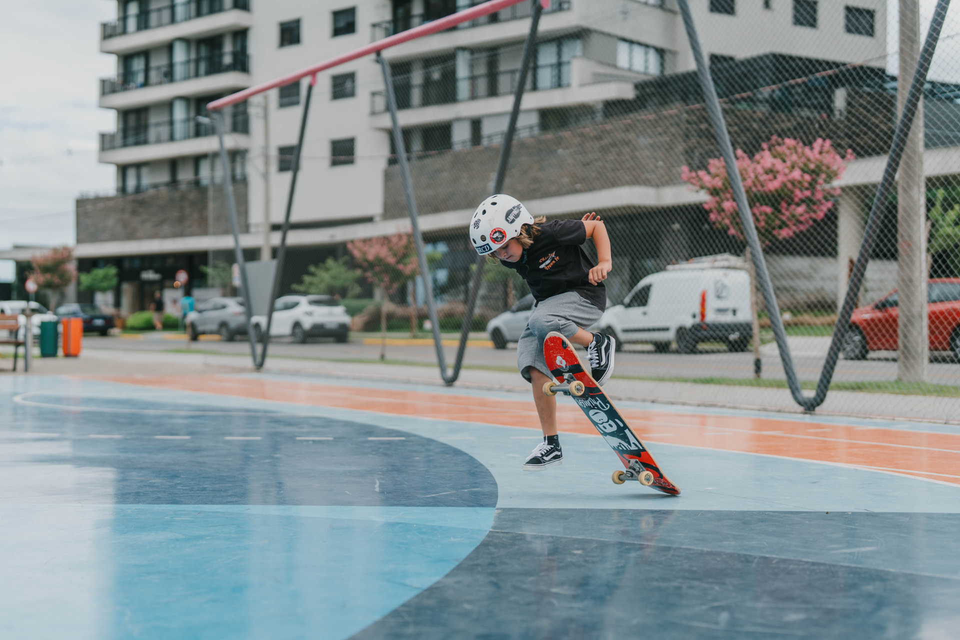 Criança de capacete fazendo manobra de skate na quadra do Parque Una