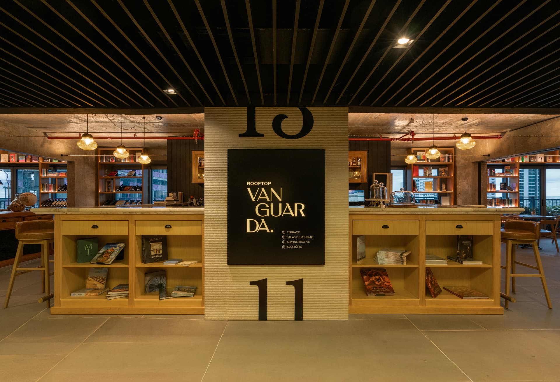 Balcão do Rooftop Vanguarda, no Parque Una, com estantes de livros iluminadas