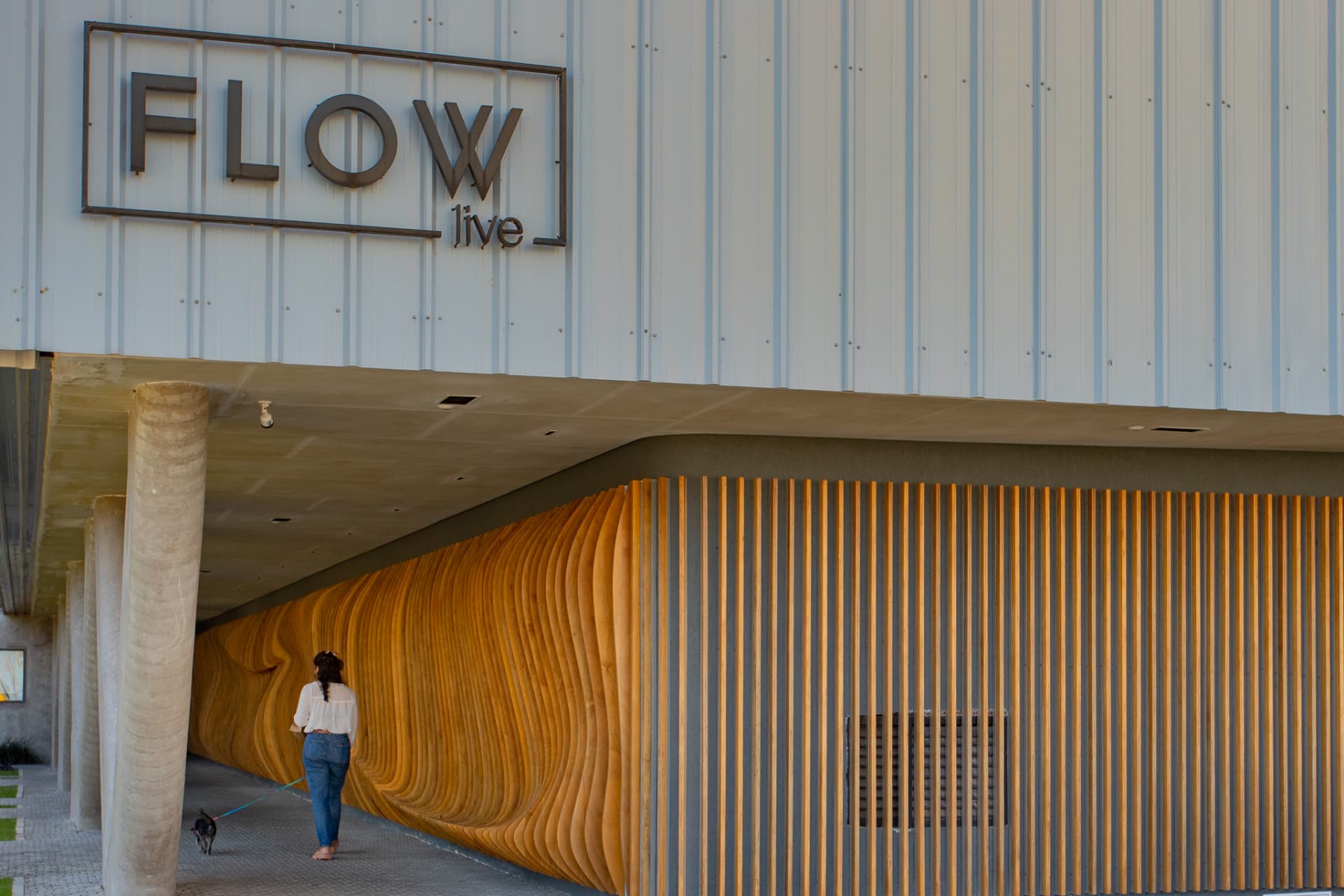 Fachada do Flow Live, no Parque Una, com painel de madeira ondulada no térreo